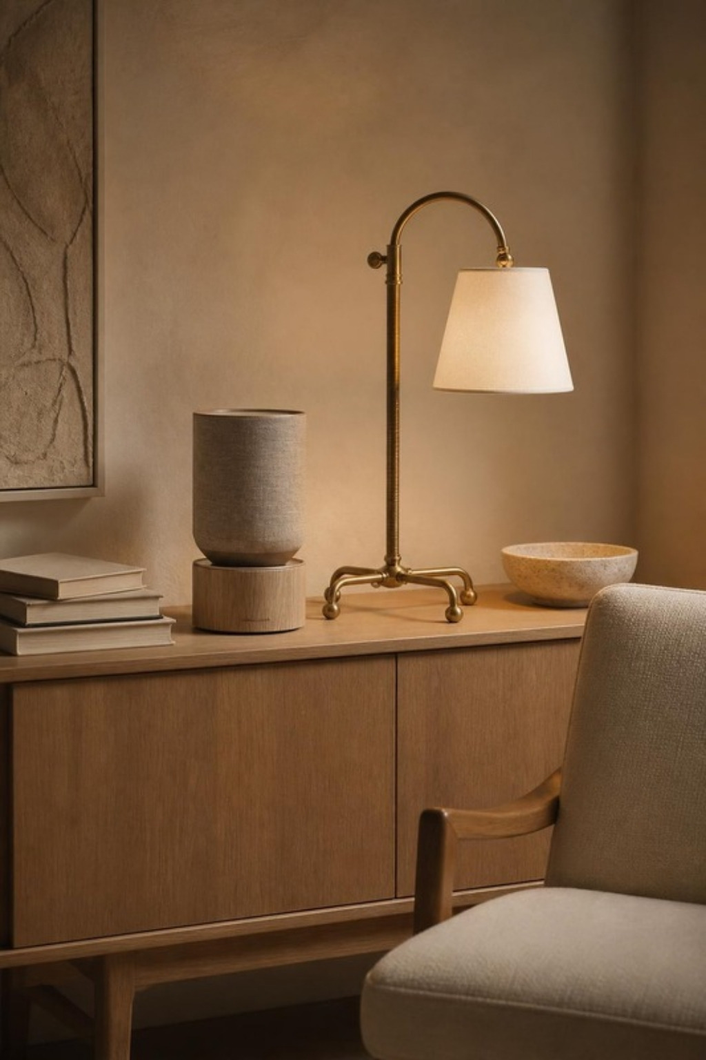 Bang and Olufsen Beosound Balance speaker on an oak console beside an aged brass table lamp with a linen shade